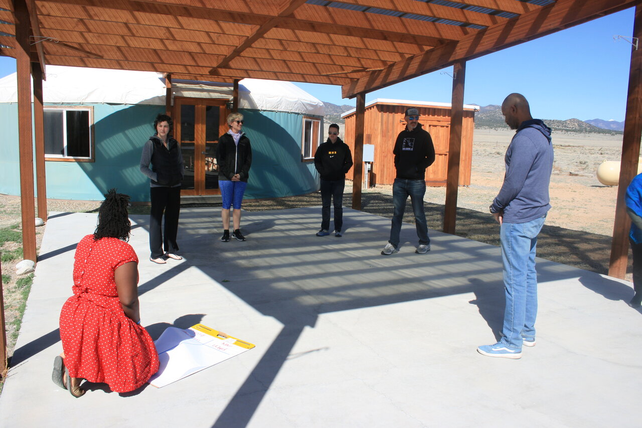 the photo shows the center of a restorative dialogue circle that is often a format used for training and discussion. Many restorative values, books, and sentimental objects of significance fill the colorful center to help ground participants during circle.